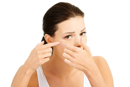 与她脸上的青春痘的年轻女子.尝试挤它照片