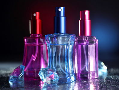 香水与颜色光暗背景上的美丽瓶中的妇女