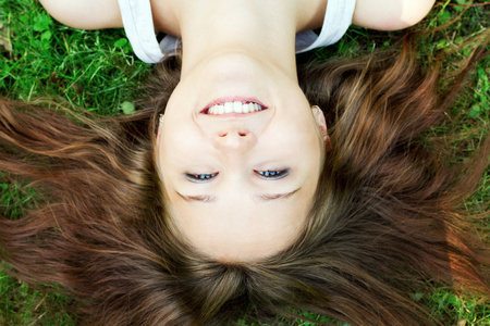美丽的微笑女孩躺在草地上