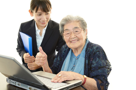 年轻女子帮助一位老妇使用一台计算机