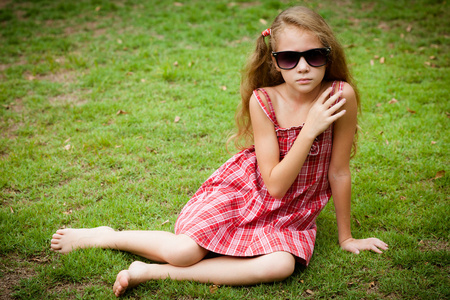 漂亮的小女孩在太阳镜和一件红色连衣裙