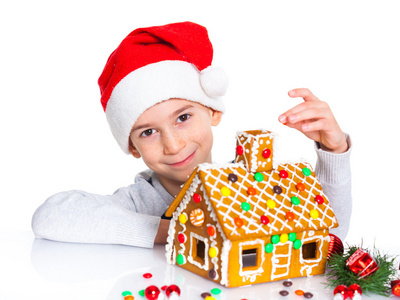 小男孩在圣诞老人的帽子与姜饼屋