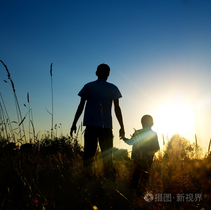 剪影父亲和儿子在日落