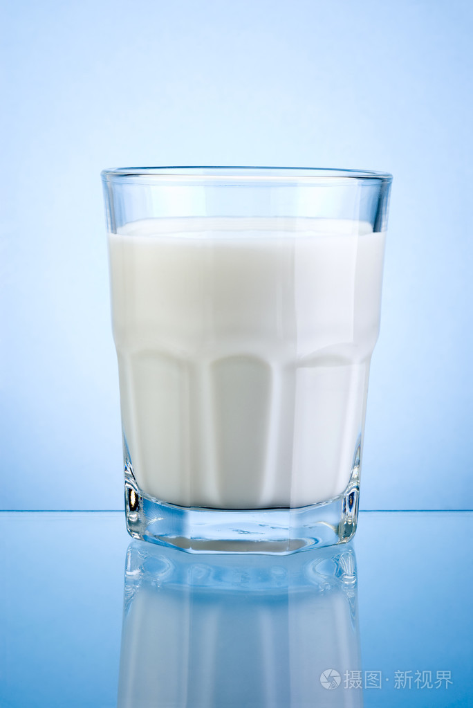 一杯新鲜的牛奶孤立在蓝色背景上