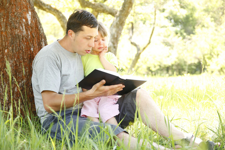 年轻的父亲与他的小女儿读圣经 