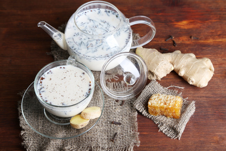 茶壶与杯茶与牛奶和香料麻布的木制桌上