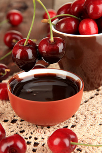 成熟的红樱桃浆果在木制表特写杯和巧克力酱