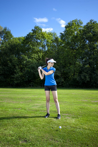 漂亮的女孩在草地上打高尔夫