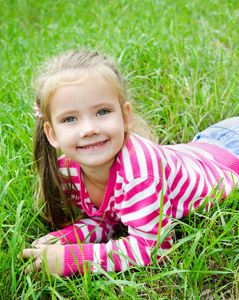 可爱微笑的小女孩躺在草地上的草