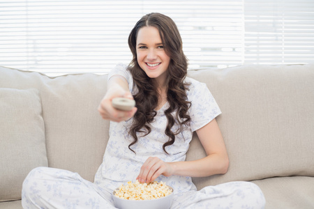 快活的女人，在观看电视时有爆米花的睡衣