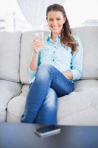 微笑着拿杯水坐在沙发上的女人