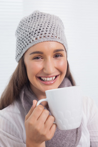 快乐的黑发女人冬季帽子上拿杯咖啡