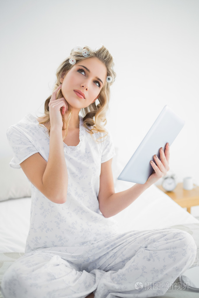 周到漂亮的金发美女戴卷发使用平板电脑