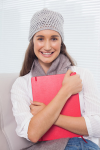 性格开朗的黑发女人冬季帽子上持有的文件夹