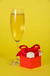 在黄色背景上喜庆的香槟和明亮礼品盒