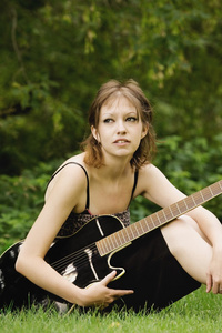 年轻女子坐在外面用的吉他