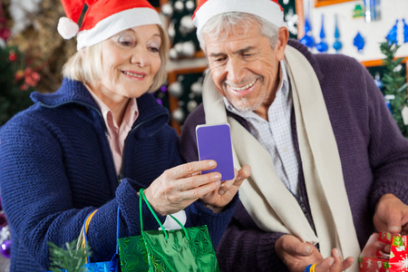 高级夫妻在圣诞节商店使用手机图片