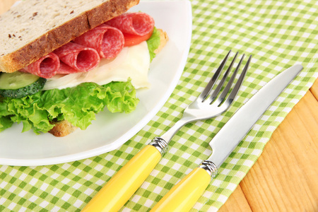 好吃的三明治与萨拉米香肠和蔬菜上白板，木制背景上