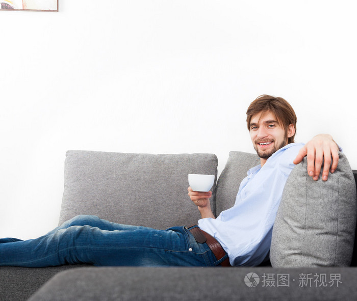 人放松的躺在沙发上喝咖啡
