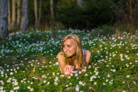 年轻漂亮的金发碧眼女人用鲜花的草地上