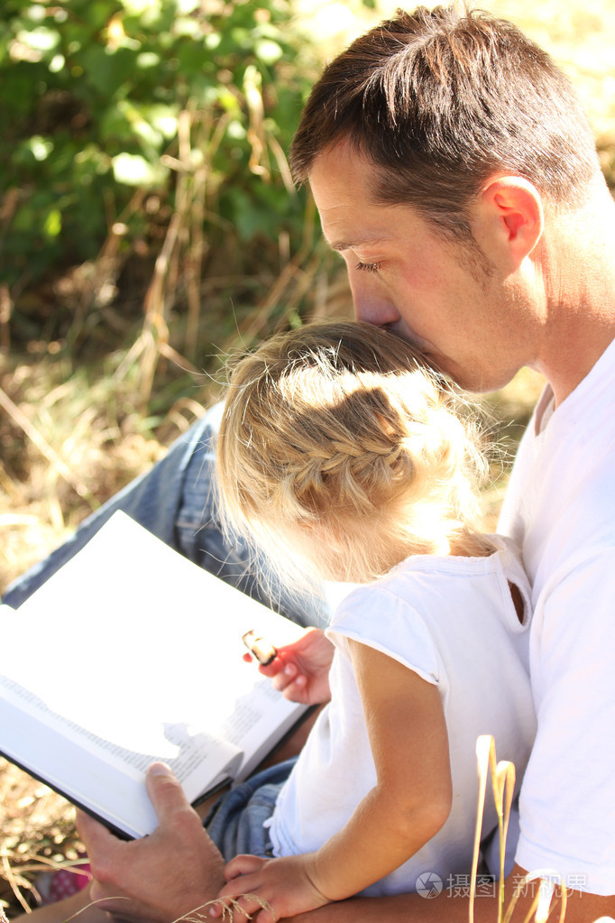 年轻的父亲与他的小女儿读圣经