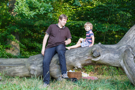 年轻的父亲和他可爱的小儿子，在夏天为在野餐