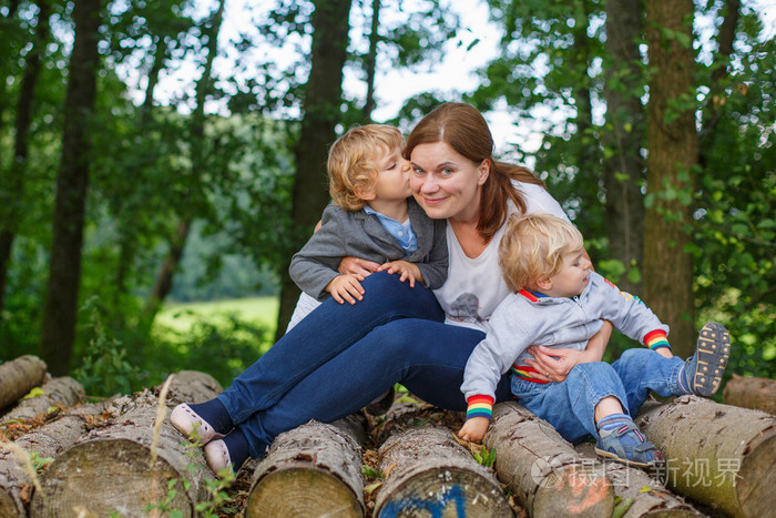 年轻的母亲和两个小男孩在夏季森林开心