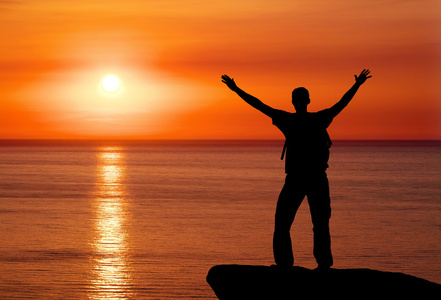 男人在山在夕阳的剪影.米的山顶上的人照片