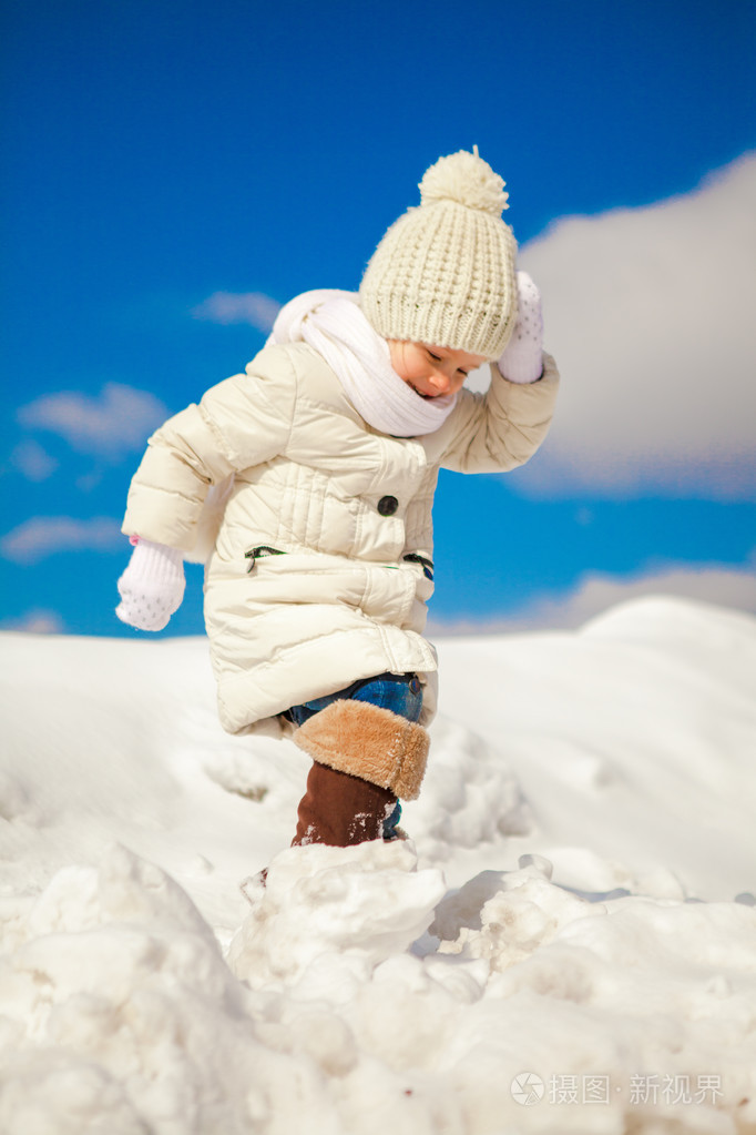 快乐的小女孩在雪地里走在阳光明媚的冬日