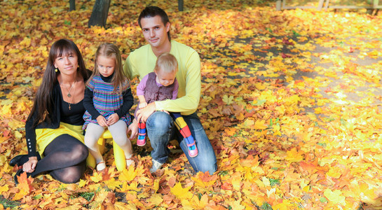 年轻迷人的家四口享受在黄色的秋天公园天气