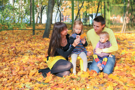 年轻迷人的家四口享受在黄色的秋天公园天气
