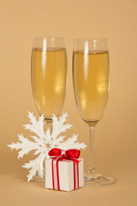 一个美丽的香槟的酒杯礼品盒用的弓和米色背景上的雪花