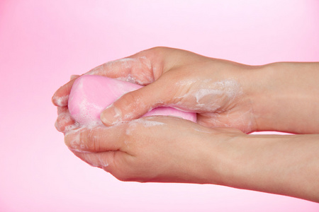一块香皂在女性手上一个粉红色的背景