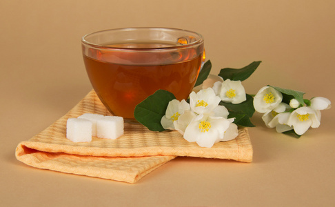 喝杯茶糖茉莉花的一个分支和米色背景上餐巾