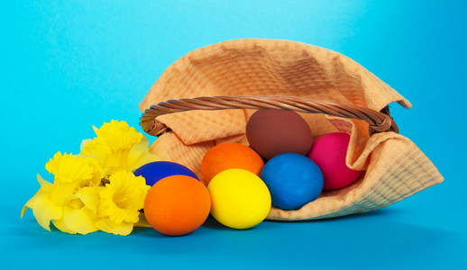 复活节彩蛋，放弃在蓝色背景上的篮子和黄色的花朵