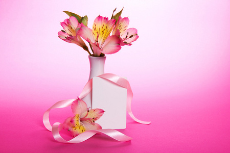 在一个花瓶和空卡用粉红色的背景上丝带粉红玫瑰