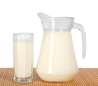水罐和玻璃与竹布，孤立在白色上牛奶