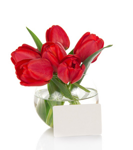 红色郁金香在一个圆形的透明花瓶和一张卡片