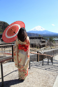 在背景中，传统红伞与富士的日本和服女人