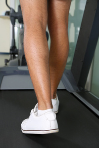 男子腿在健身房的跑步机上