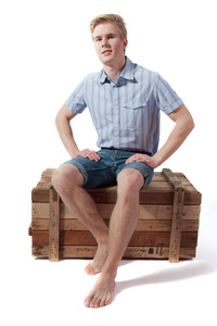 年轻男子坐在木箱子上