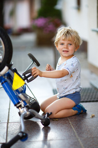 蹒跚学步的小男孩，修复他的第一辆自行车