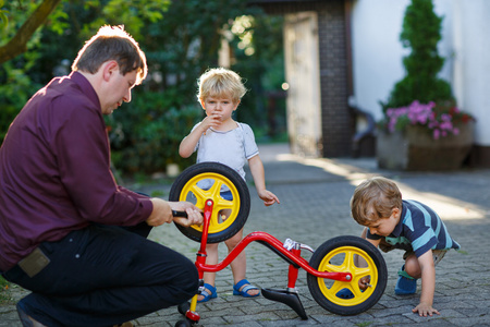 两个可爱的男孩修理自行车轮与父 ou 的肖像
