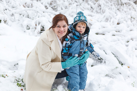 年轻女子和她的小儿子开心与雪在冬天 fo