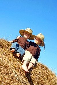 快乐的大哥哥和孩子坐在外面捆草
