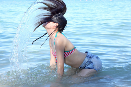 年轻漂亮的女孩儿溅在海中的水