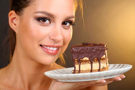 巧克力蛋糕棕色背景上的漂亮年轻女孩的肖像