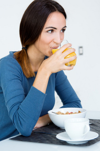 年轻女人享受在厨房里的橙色 juicet