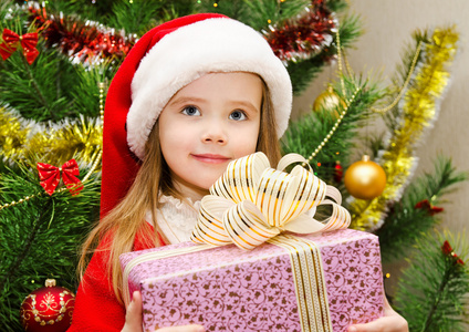 礼物的圣诞老人帽子的小女孩过圣诞节