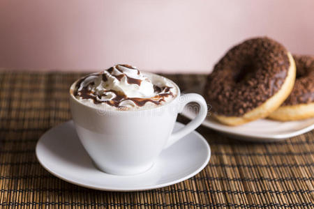 一杯加奶油和坚果的巧克力甜甜圈的咖啡